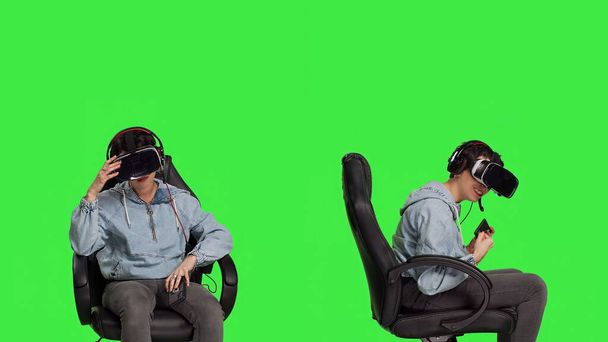 Woman gamer losing and winning at mobile video games against greenscreen backdrop, playing with virtual reality headset. Girl feeling cheerful and disappointed with win and failure. Camera B. - Photo, Image