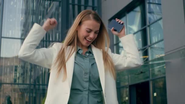 Heureuse femme femme d'affaires caucasienne gagnante excitée fille étudiante célébrant la victoire en se réjouissant de réussite dansant en ville en plein air gagner de bonnes nouvelles grand résultat atteindre le succès commercial - Séquence, vidéo