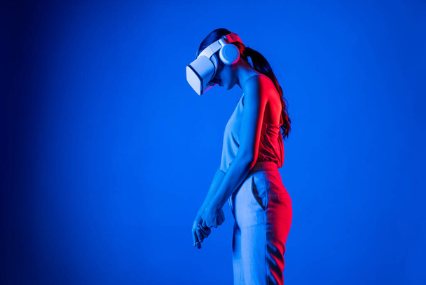 Okos női álló visel VR headset összekötő metaverse, jövő kibertér közösségi technológia. Elegáns nő számítása és ellenőrzése virtuális putter komolyan golfozni. Hallucináció. - Fotó, kép