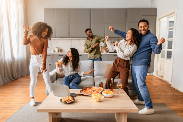 Un gruppo di giovani multirazziali viene visto ballare e divertirsi insieme in un gruppo di amici che si riuniscono a casa - Foto, immagini