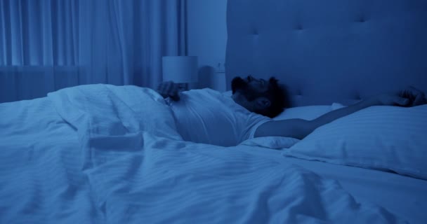 Σε πραγματικό χρόνο απογοητευμένοι γενειοφόρος ενήλικος άνδρας που πάσχουν από αϋπνία κοιτάζοντας μακριά, ενώ βρίσκεται στην πλευρά στροφή στο κρεβάτι και αδυνατεί να κοιμηθεί τη νύχτα στο δωμάτιο - Πλάνα, βίντεο