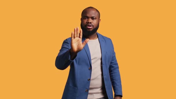 Stern african american man doing stop hand gesture sign. Annoyed BIPOC person doing firm halt sign gesturing, wishing to end concept, isolated over studio background, camera B - Footage, Video