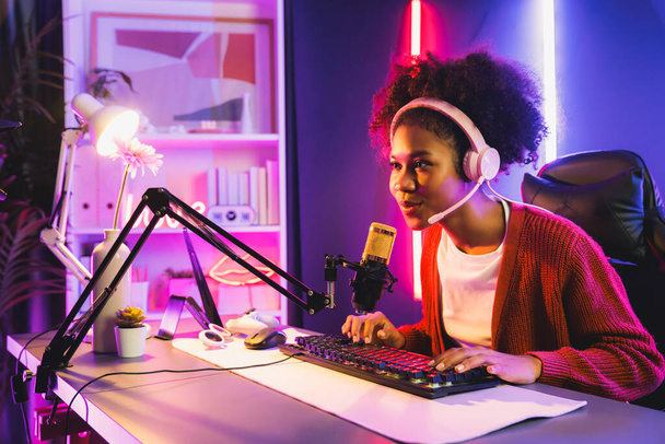 Afrikai amerikai lány streamer online játszik harcol Esport képzett csapat visel fejhallgató neon színű világítás szoba. Beszélgetni más játékosokkal stratégiákat tervez, hogy megnyerje a versenytársakat. Kóstoló. - Fotó, kép