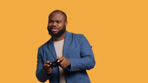 Vrolijke Afrikaanse Amerikaanse gamer met duimen omhoog teken gebaren holding controller, het spelen van videogames. Joyful persoon enthousiast om te doen gaming, doen goedkeuring van de hand gebaar, studio achtergrond, camera A - Video