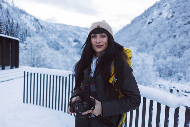 Een portret van een glimlachende vrouwelijke fotografe die haar camera vasthoudt, klaar om de winterschoonheid om haar heen vast te leggen. - Foto, afbeelding