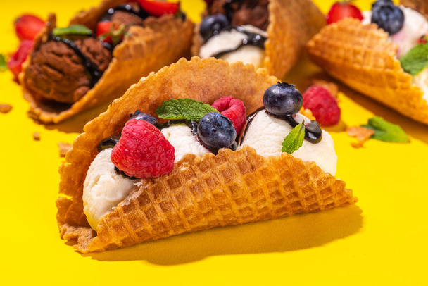 Varios helados de tacos dulces. Conchas de tacos de gofre con helado de chocolate y sabor vainilla con diferentes frutas, bayas, coberturas - Foto, Imagen