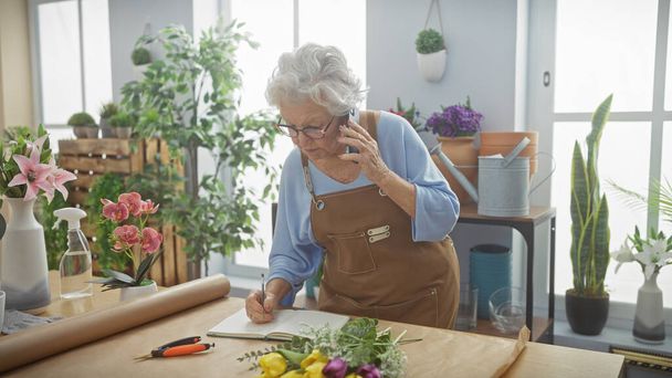 Senior woman florist taking order over phone in flower shop - Fotoğraf, Görsel