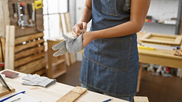 Afričanky americká žena nosí bezpečnostní rukavice v dřevoobráběcí studio - Fotografie, Obrázek