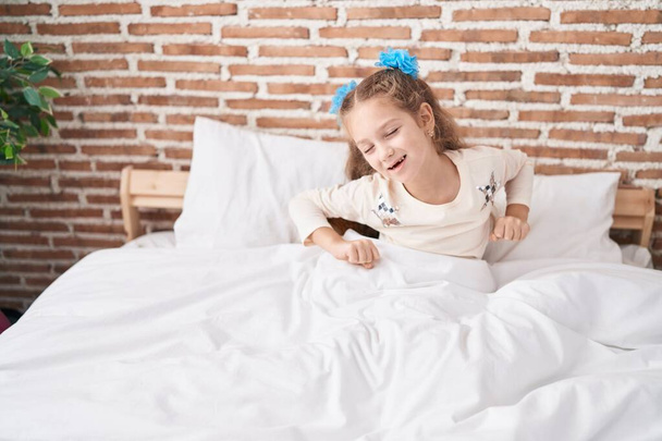 Adorabile ragazza caucasica svegliarsi allungando le braccia in camera da letto - Foto, immagini