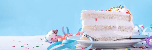 tranche de gâteau d'anniversaire sur table décorée de fête d'anniversaire. Tranche de gâteau d'anniversaire avec crème fouettée blanche, saupoudrer de sucre funfetti et bougie, espace de copie - Photo, image