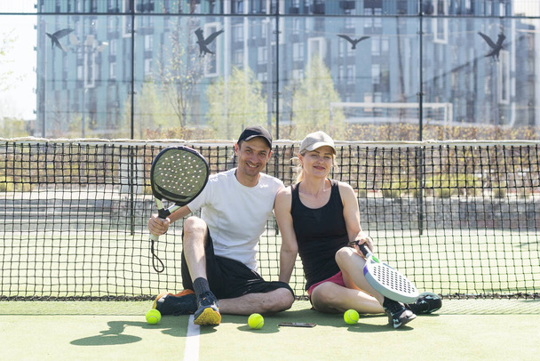 テニスコートにポーズするパネルラケット付きスポーツカップル. 高品質の写真 - 写真・画像