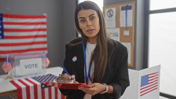 Mulher hispânica com adesivo 'eu votei' tomando notas no centro universitário eleitoral americano com bandeiras. - Foto, Imagem