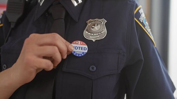 Un primer plano de un oficial de policía adjuntando una etiqueta de "votado hoy" a su uniforme, que simboliza el deber cívico y la participación de las fuerzas del orden en la democracia. - Foto, imagen