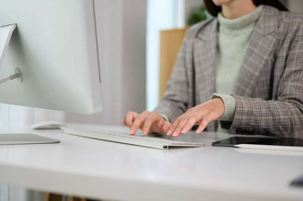 Jonge zakenvrouw op zoek naar computerscherm, werken op afstand op moderne thuiskantoor. - Foto, afbeelding