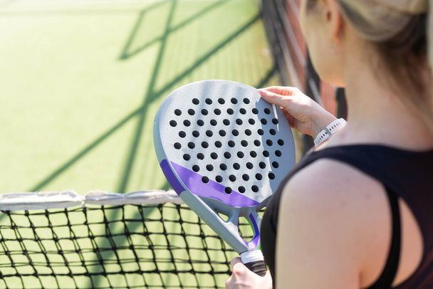 manos de una mujer jugador de pádel está sosteniendo bolas y la raqueta en el fondo al principio del partido al aire libre. Foto de alta calidad - Foto, Imagen