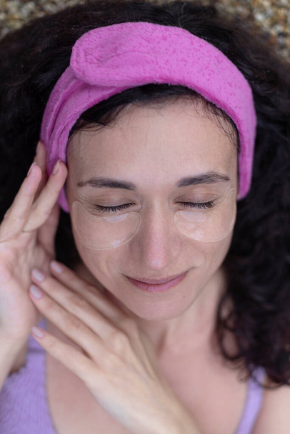 Uma mulher com manchas nos olhos no rosto usando em um ambiente de spa. - Foto, Imagem