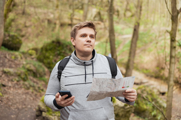 Młody człowiek próbuje znaleźć sygnał telefoniczny w lesie. Poszukiwanie mobilnych połączeń w dzikiej przyrodzie na wakacjach. Wściekły człowiek turysta trzyma sygnał wyszukiwania smartfona - Zdjęcie, obraz