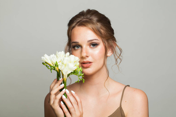 Vrolijke jonge volwassen vrouw met schone, frisse huid met bloem. Model met gezonde huid close-up. Cosmetologie, schoonheid en spa. - Foto, afbeelding