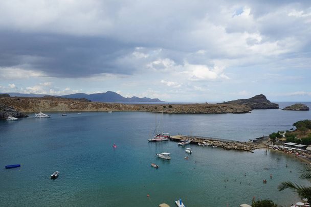 Widok na plażę Lindos w sierpniu. Lindos jest stanowiskiem archeologicznym, wioską rybacką i byłą gminą na wyspie Rodos, w Dodekanezie, Grecja. - Zdjęcie, obraz