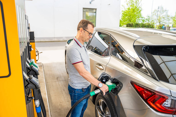 Kuljettaja tankkaa kallista bensiiniä itsepalveluhuoltoasemalla Euroopassa. Laadukas kuva - Valokuva, kuva