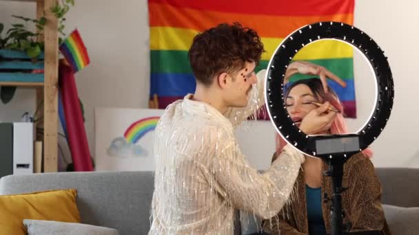 Een paar werkt samen aan een creatieve make-up look, met een vrouw die een man voor een ringlicht begeleidt. - Video