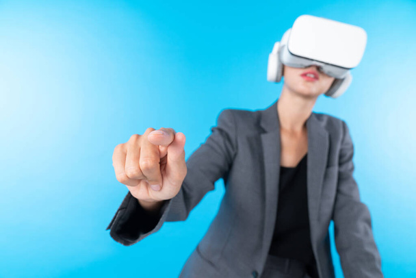 Kierownik projektu nosi słuchawki VR i stoi, wskazując hologram innowacyjnej technologii. Inteligentna bizneswoman łączy się ze światem rzeczywistości wizualnej patrząc na dane do inwestycji. Konstrukcja. - Zdjęcie, obraz