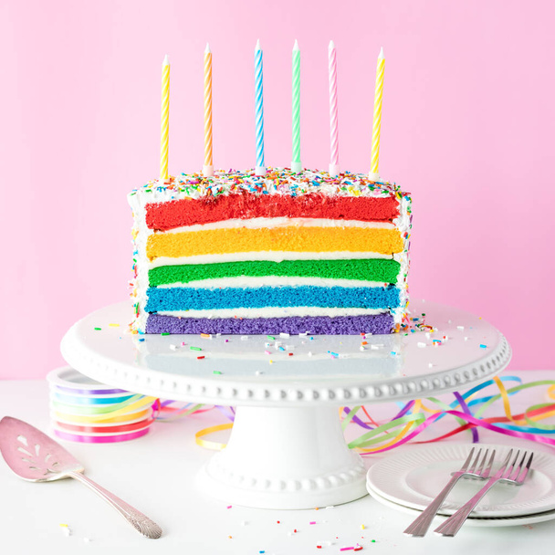 Světlý barevný duhový narozeninový dort s nezapálenými svíčkami, připravený na oslavu. - Fotografie, Obrázek