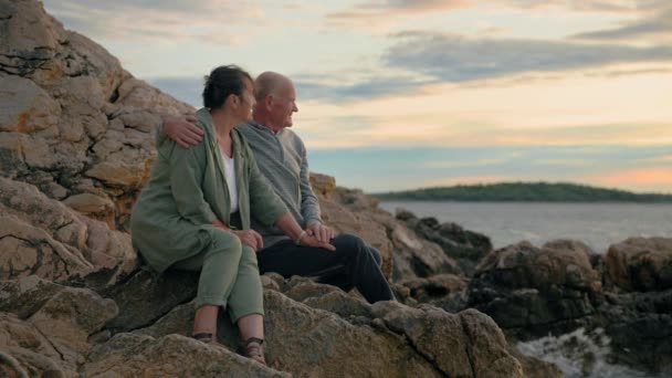 Rentner im Urlaub, alte, liebende Männer und Frauen genießen gemeinsam den Sonnenuntergang, während sie an warmen Abenden am Strand sitzen - Filmmaterial, Video