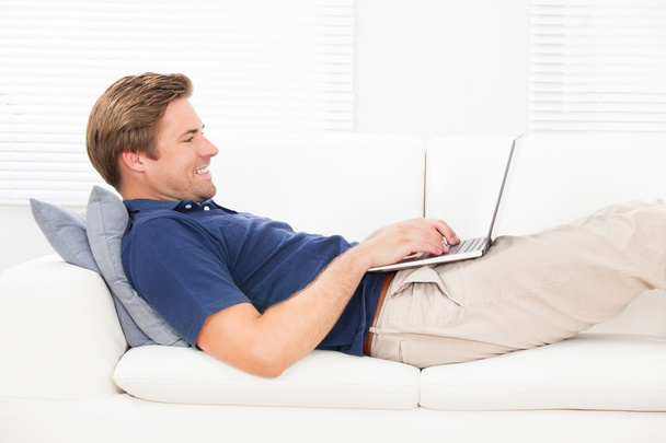 Smiling Man Using Laptop On Sofa - Foto, imagen