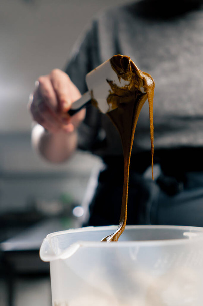 крупним планом на професійній кухні пекар виймає арахісове масло з шпателем - Фото, зображення