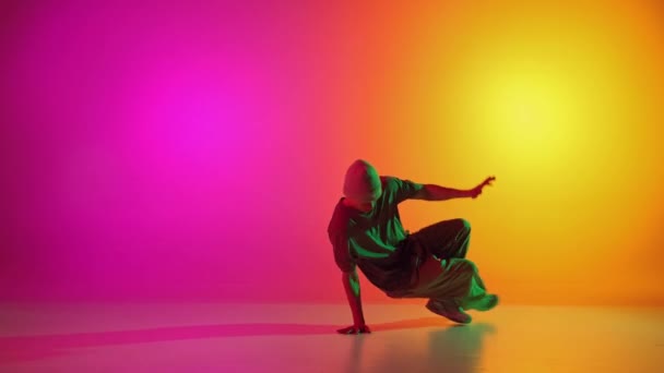 Breakdance performansının yaratıcı, dinamik videosu, neon ışıkta, gradyan pembe-sarı arka plana karşı donuyor. Sanat, hobi, spor, yaratıcılık, moda ve tarz, eylem kavramı. Ad - Video, Çekim