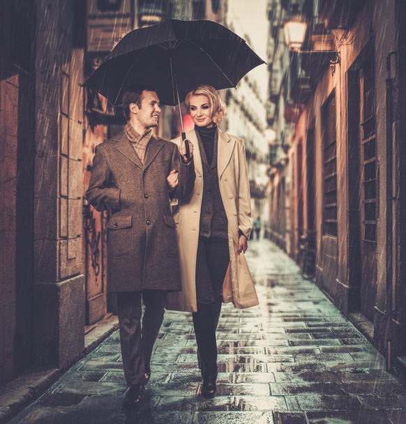 Couple élégant avec parasol marchant à l'extérieur sous la pluie
 - Photo, image