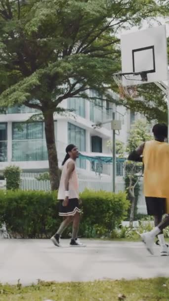Pystysuora laukaus kaksi mustaa kaveria pelaa streetball valmistautuessaan ottelu ulkona - Materiaali, video