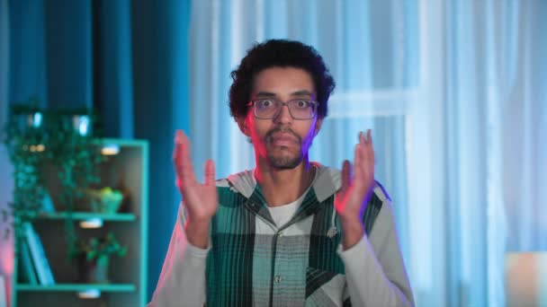 чорний молодий чоловік в окулярах показує емоції несподіванки, дивлячись на камеру - Кадри, відео