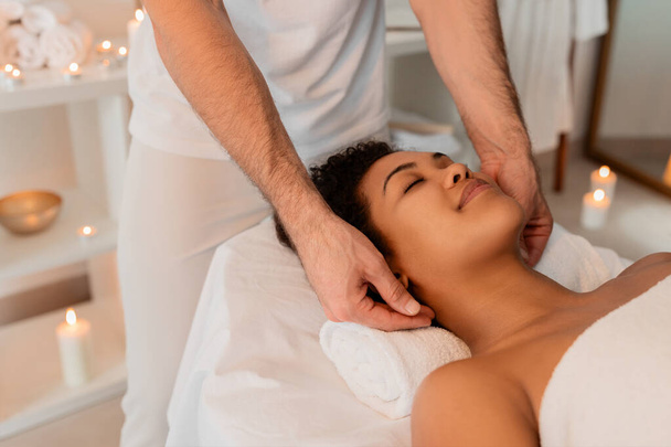Um terapeuta especialista está dando uma massagem no ombro a uma senhora afro-americana em um ambiente de spa sereno, pessoas desfrutando de bem-estar - Foto, Imagem