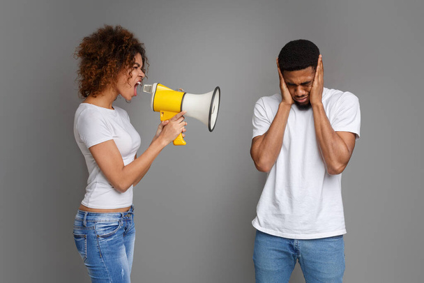 Problemas de comunicación. Chica afroamericana gritando a través de megáfono a su novio, fondo gris - Foto, Imagen