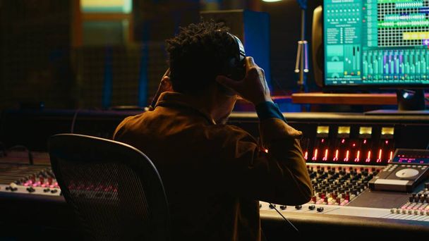 African american sound designer removing tonal imbalances and white noise on recorded files, music industry post production in professional studio. Control room expert editing tracks. Camera A. - Photo, Image