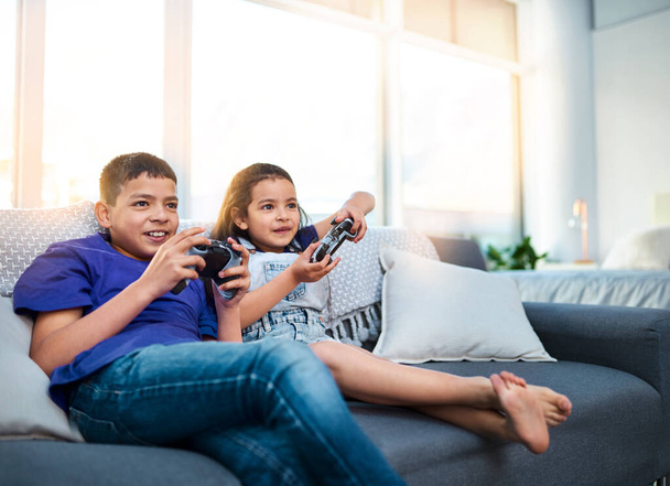 Παιδιά, αδέλφια και video game με χειριστήριο, καναπέ και online για esports στο σπίτι. Τεχνολογία, ψυχαγωγία και εικονική πρόκληση για τον αδελφό και την αδελφή, κονσόλα ή καναπέ στο σαλόνι για διασκέδαση. - Φωτογραφία, εικόνα