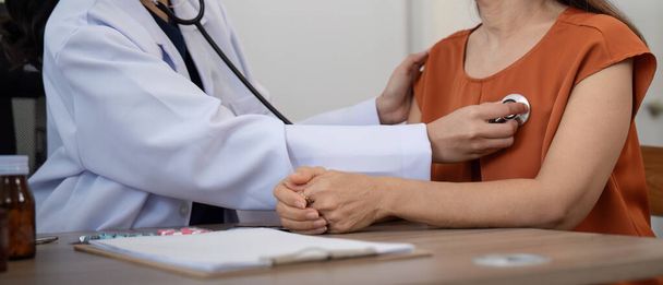 Donna anziana paziente asiatico sono check-up di salute, mentre una donna medico utilizzare uno stetoscopio per sentire la frequenza cardiaca. concetto di assistenza sanitaria agli anziani. - Foto, immagini