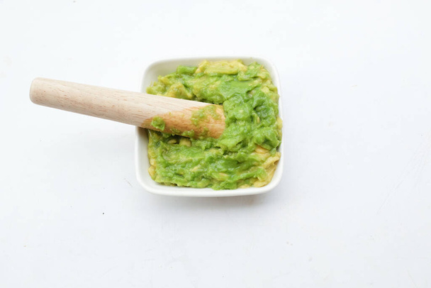 Babynahrung frische grüne Avocado püriert in einer kleinen Keramikschüssel isoliert auf einem weißen Rücken. Gesunde Babynahrung, Gemüse und Obst Ideen. - Foto, Bild