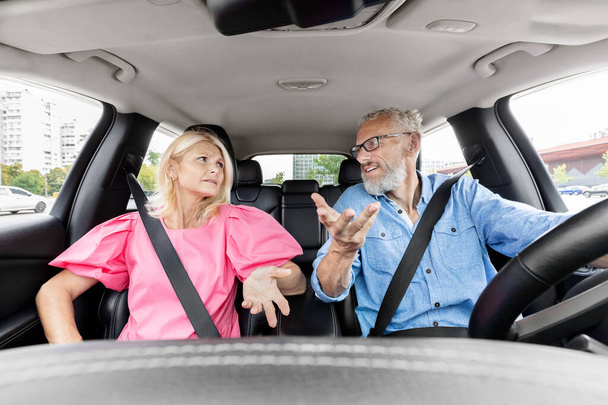 Úgy tűnik, egy idősebb pár nézeteltérésben van, miközben a férfi vezet, és a nő rosszallóan néz ki. - Fotó, kép