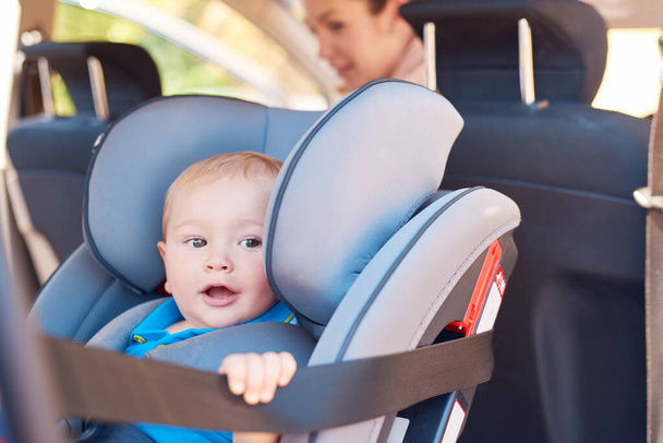 Cute, baby and car seat with mother for safety, travelling and transportation. Happy, toddler and woman together in vehicle for road trip, adventure or drive to play date or park for bonding. - Photo, Image
