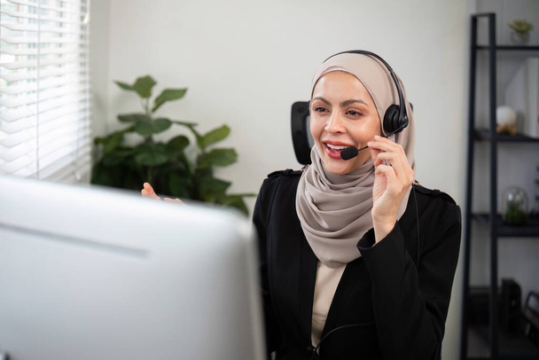 Giovani donne musulmane che indossano hijab telemarketing o agente call center con auricolari che lavorano su hotline di supporto in ufficio. - Foto, immagini