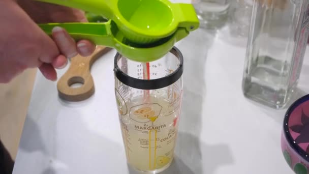Esprema um limão sobre um copo de medição para fazer uma margarita. - Filmagem, Vídeo