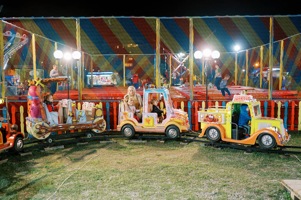 Küçük çocuklar lunaparktaki oyuncak treninde at arabalarına biniyorlar. Yüksek kalite fotoğraf - Fotoğraf, Görsel