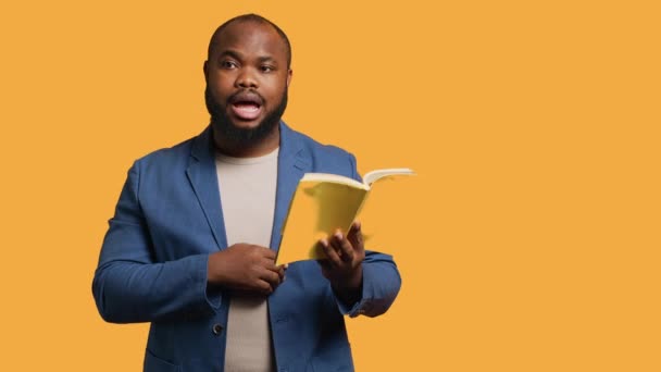 Африканський американський оратор читає книгу вголос, розповідаючи історію для аудиторії. Людина BIPOC представляє літературний роман, читає зі сторінок, розважає глядачів, студійний фон, камеру А - Кадри, відео