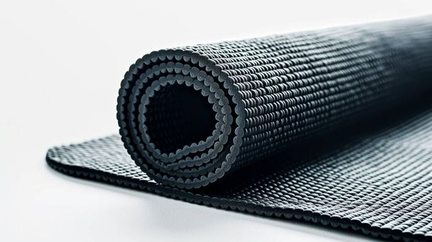 Hengerelt fekete jóga szőnyeg texturált felülettel fehér alapon. - Fotó, kép