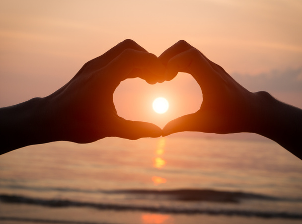 Para, trzymając ręce serce miłości na zachód słońca na plaży, Walentynki - Zdjęcie, obraz