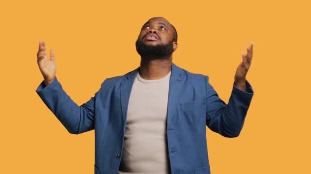 Cheerful pious african american man looking up to sky, waiting for sign from his god. Happy spiritual man doing worship hand gesturing, hoping for miracle, isolated over studio background, camera A - Footage, Video