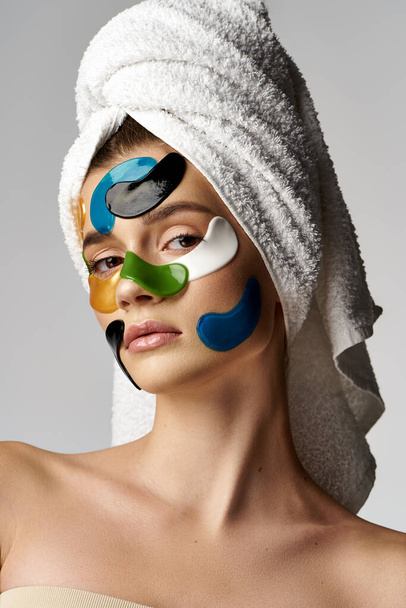 Uma jovem com manchas nos olhos no rosto, usando uma toalha na cabeça em uma pose serena. - Foto, Imagem